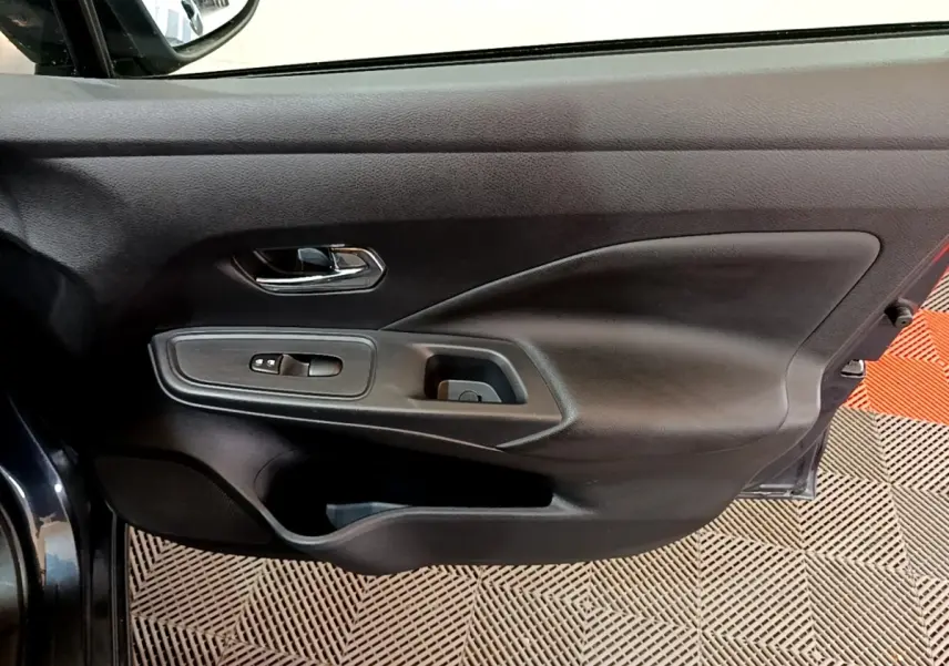 Vue rapprochée de la porte avant gauche gris foncé de la Nissan Micra 2020 avec commandes de vitres et poignée chromée.
