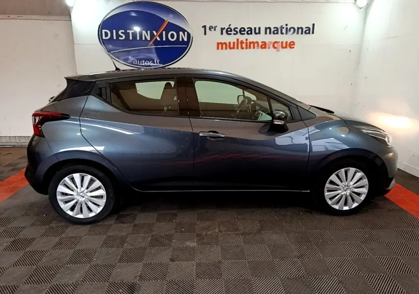 Profil droit d'une Nissan Micra IG-T 100 Business Edition gris foncé, en intérieur sur sol carrelé noir et rouge.