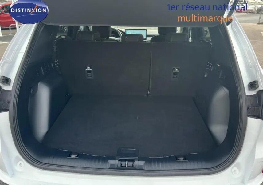 Coffre ouvert vu de l'arrière d'un Ford Kuga blanc 2025, avec banquette arrière noire et espace de chargement vide.