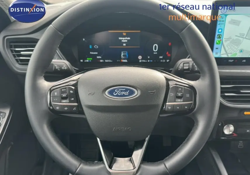 Vue rapprochée du volant noir de la Ford Kuga 2025 avec tableau de bord numérique et écran tactile latéral.