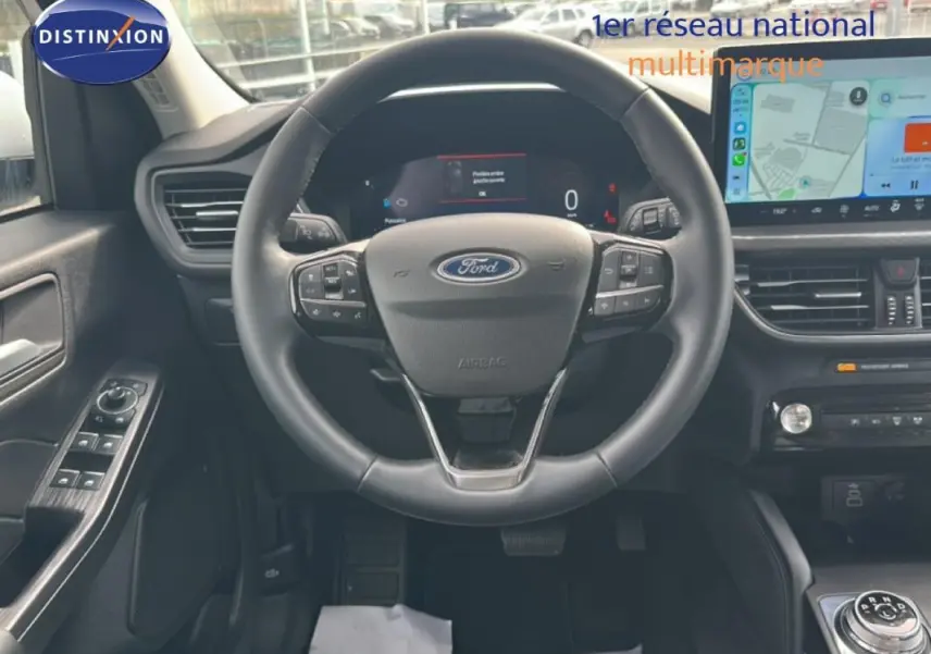 Vue intérieure centrée sur le volant noir du Ford Kuga 2025 avec écran tactile et commandes au volant visibles.