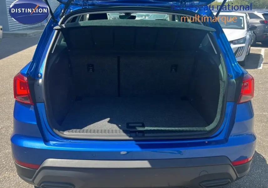 Vue arrière du coffre ouvert d'un SEAT Arona bleu saphir métal avec toit noir, montrant l'espace de chargement vide.
