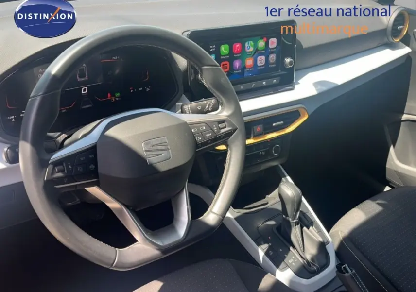 Vue intérieure du poste de conduite du SEAT Arona 2025, volant cuir, écran tactile et levier de boîte automatique.