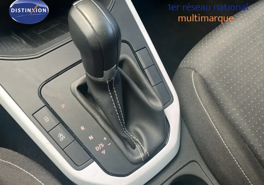 Gros plan sur la console centrale et levier de vitesse automatique du SEAT Arona 2025, intérieur tissu gris.