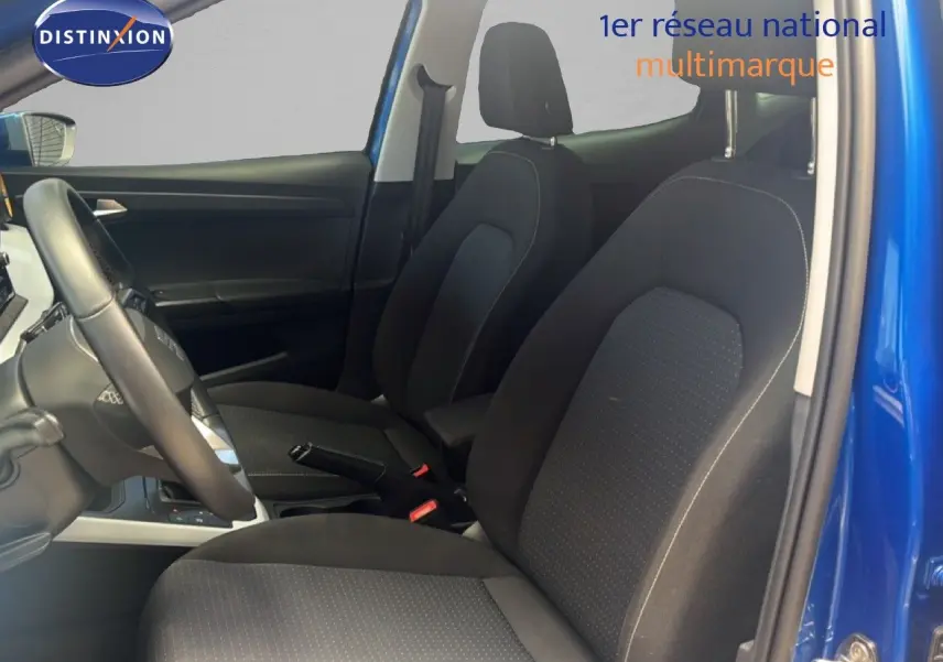 Vue intérieure côté conducteur du SEAT Arona bleu saphir avec sièges en tissu noir et volant cuir.