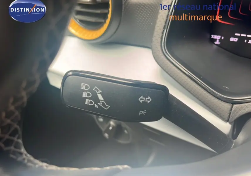 Gros plan sur la commande des clignotants et feux, côté gauche du volant du SEAT Arona bleu saphir 2025.
