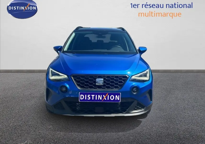 Vue avant d'un SEAT Arona bleu saphir métallisé avec calandre noire et toit noir visible en arrière-plan.