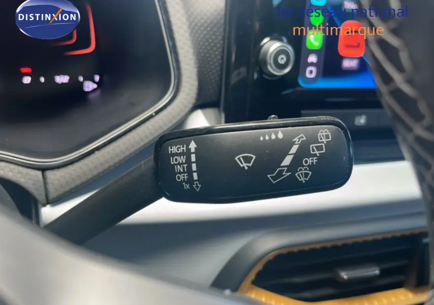 Gros plan sur la commande d’essuie-glace du SEAT Arona 2025, intérieur noir avec écran tactile en arrière-plan.