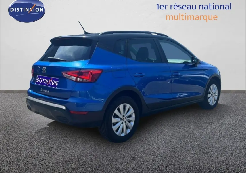 Vue 3/4 arrière droite d'un SEAT Arona bleu saphir avec toit noir, sur fond neutre en extérieur.