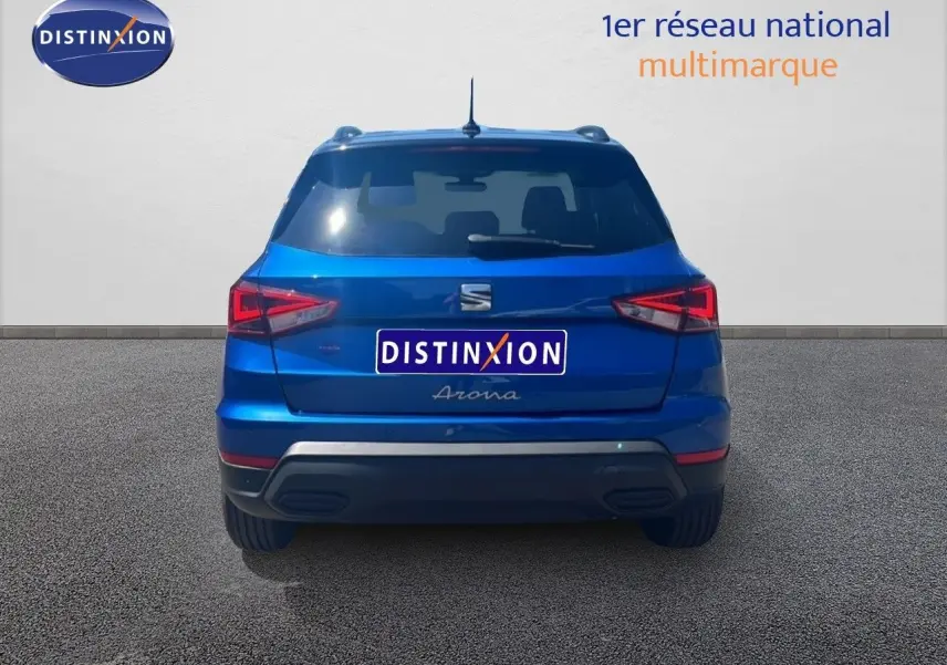 Vue arrière d'une SEAT Arona bleu saphir métal avec toit noir, montrant ses feux arrière et son logo central.