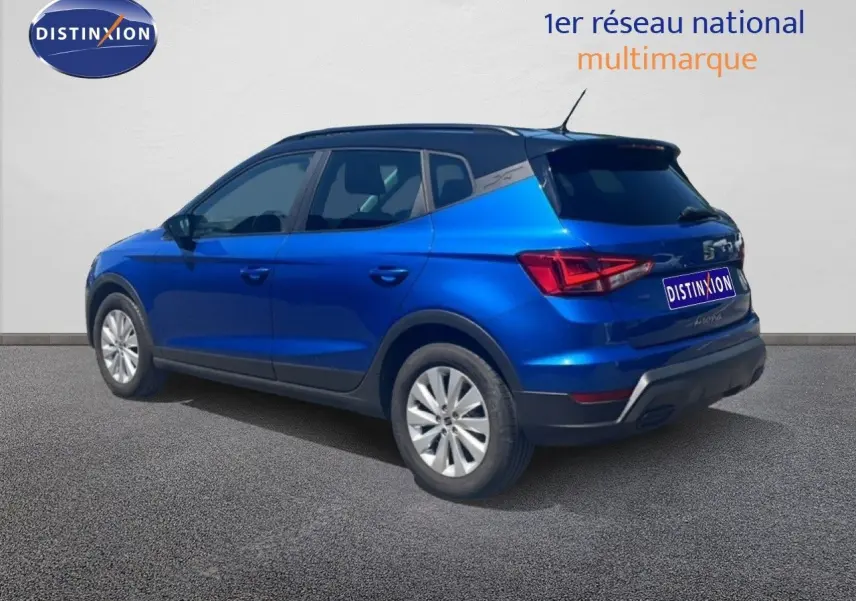 Vue 3/4 arrière droite d’un SEAT Arona bleu saphir avec toit noir, sur fond neutre extérieur.