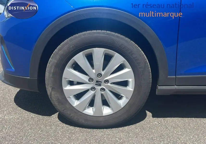 Gros plan sur la roue avant gauche d’un SEAT Arona bleu saphir avec jante alu et entourage noir.