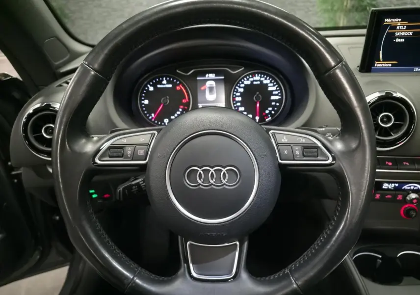 Vue rapprochée du volant cuir noir multifonction et du tableau de bord d'une Audi A3 Cabriolet gris foncé de 2015.