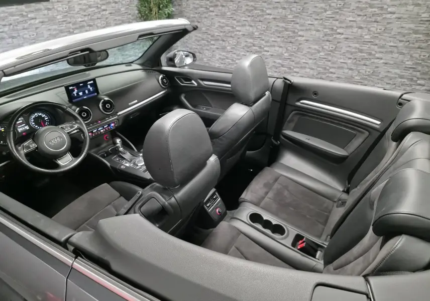 Vue intérieure de l'Audi A3 Cabriolet gris foncé, montrant les sièges en alcantara/cuir et le tableau de bord moderne.