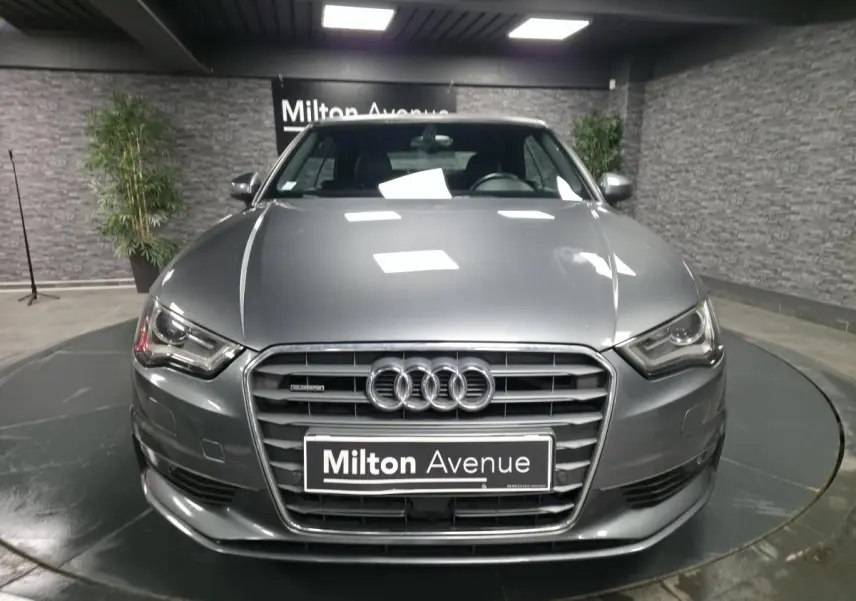 Audi A3 Cabriolet gris foncé vue de face en intérieur avec calandre Singleframe et logo Audi bien visibles.