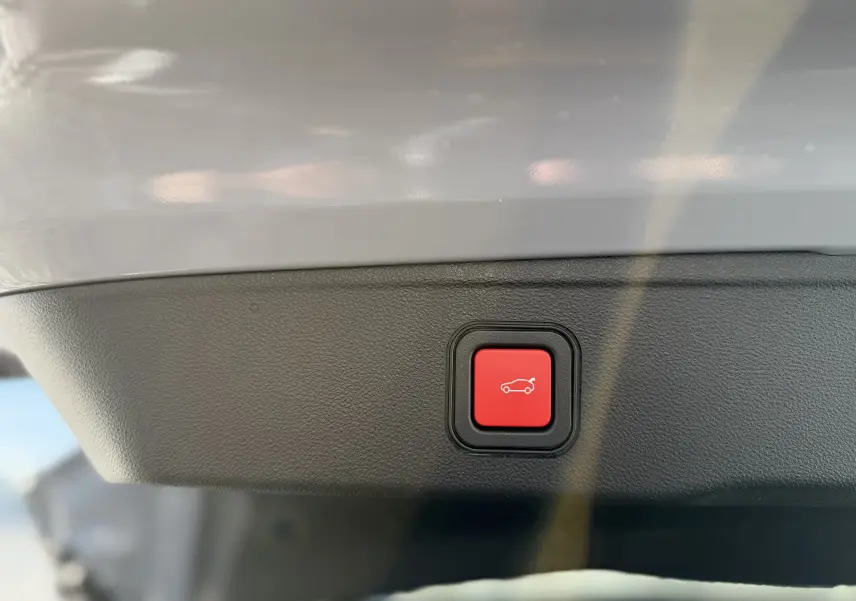 Bouton rouge de fermeture électrique du hayon sur le panneau intérieur d’un Jeep Avenger gris Storm Grey.