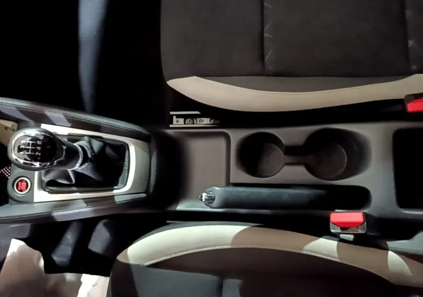Vue plongeante sur la console centrale noire de la Nissan Micra IG-T 90 N-Connecta avec levier de vitesse manuel et sièges bicolores.