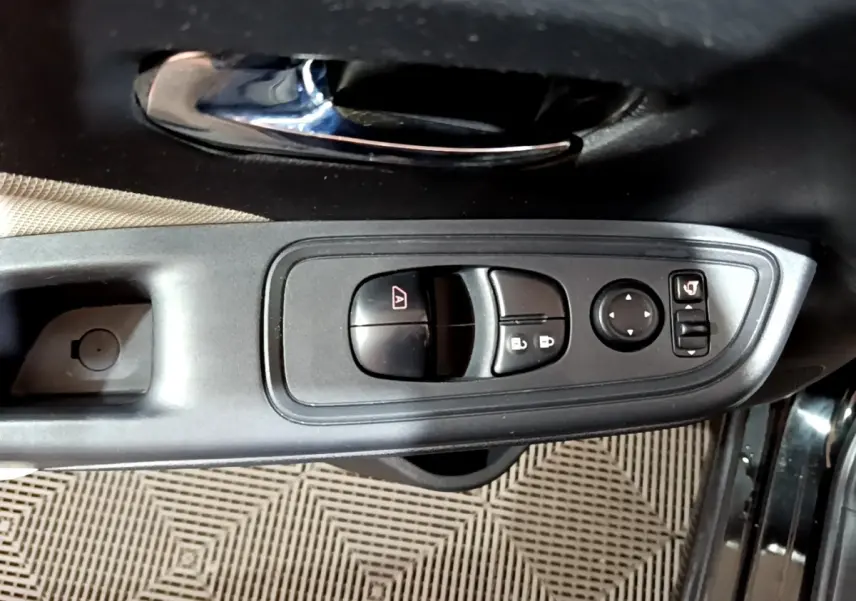 Vue rapprochée de la commande des vitres et rétroviseurs sur la porte côté gauche d'une Nissan Micra noire.