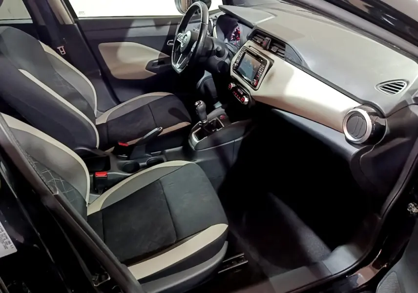 Vue intérieure côté conducteur de la Nissan Micra IG-T 90 N-Connecta noire, avec tableau de bord clair et volant cuir multifonctions.