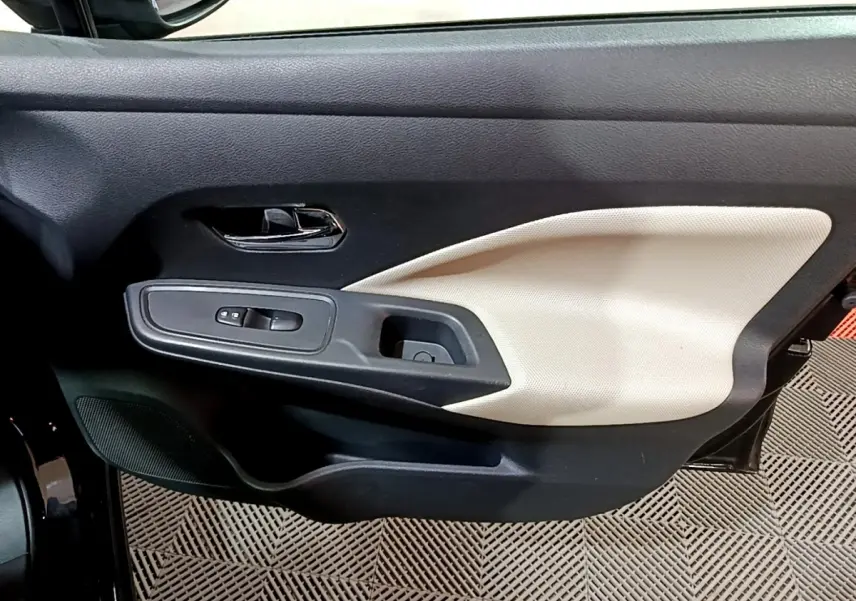 Vue rapprochée de la porte avant gauche de la Nissan Micra noire, avec insert beige et commandes de vitres.