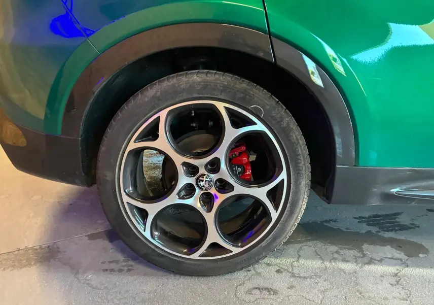 Gros plan sur la roue arrière droite d'une Alfa Romeo Tonale vert foncé, avec étrier de frein rouge visible.