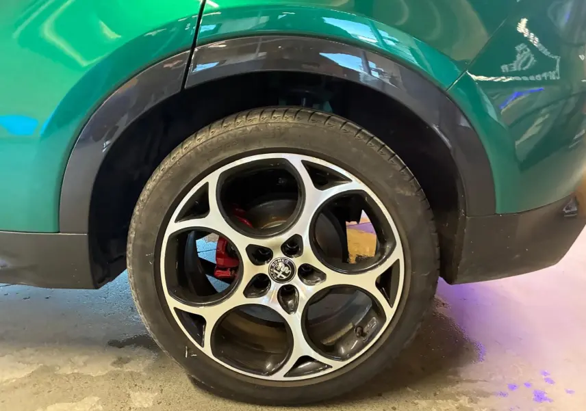 Gros plan sur la roue arrière droite d'une Alfa Romeo Tonale vert foncé avec jante alliage et étrier de frein rouge.