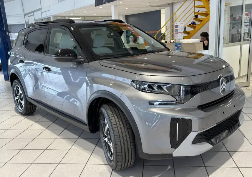 Vue 3/4 avant d'un Citroën C3 Aircross 2026 gris métallisé avec toit noir et jantes alliage 17 pouces.