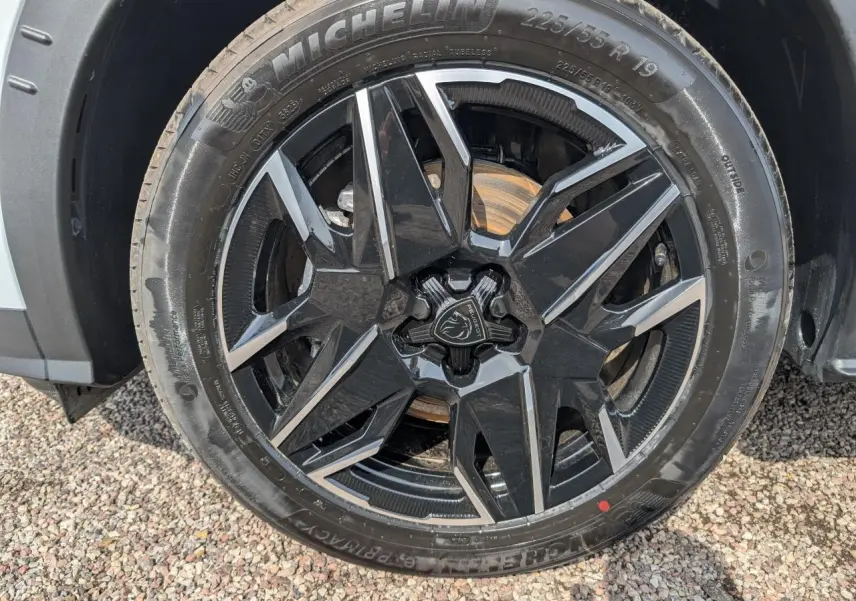 Gros plan sur la jante alliage noire et diamantée 19'' du Peugeot 5008 blanc hybride, avec pneu Michelin visible.
