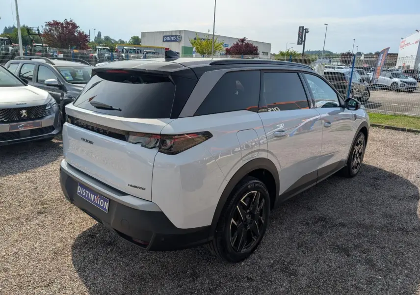 Vue 3/4 arrière droite du Peugeot 5008 blanc hybride 2025 avec toit noir et jantes alliage noires diamantées.