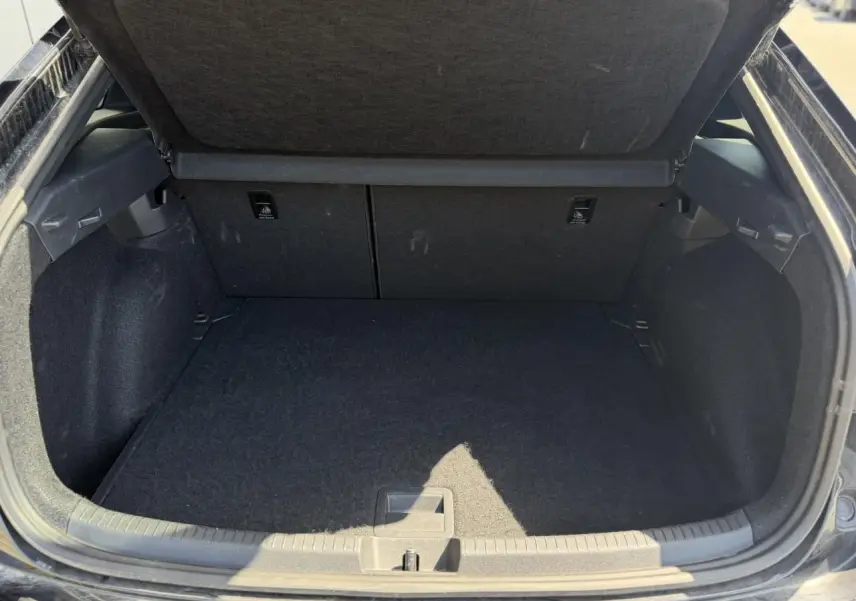 Coffre ouvert vu de l'arrière d'un Volkswagen Taigo noir, espace de chargement propre et vide.