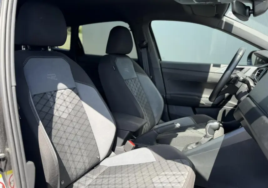 Vue intérieure côté gauche des sièges avant en tissu R-Line gris et noir du Volkswagen Taigo TSI 116 DSG 2025.