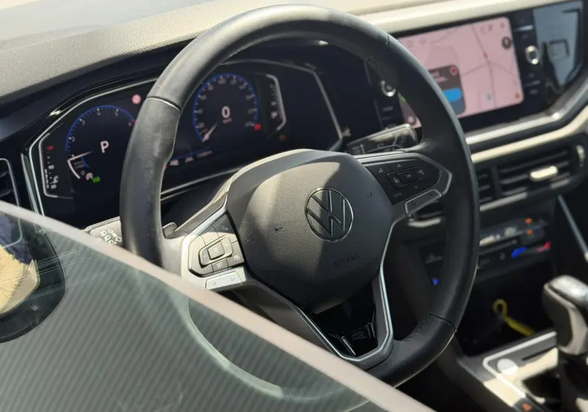 Vue intérieure centrée sur le volant cuir multifonctions et le tableau de bord digital du Volkswagen Taigo noir 2025.