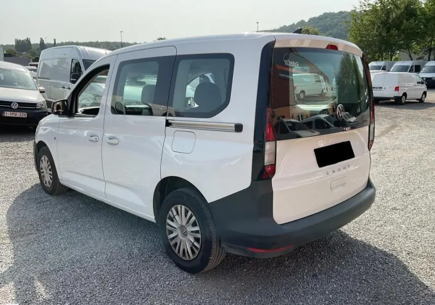 Vue 3/4 arrière droite d'un Volkswagen Caddy blanc Candy 2024 avec hayon vitré et portes coulissantes.