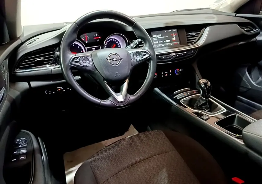Vue intérieure avant de l’Opel Insignia 2019, tableau de bord noir avec volant cuir et levier de vitesse manuel.