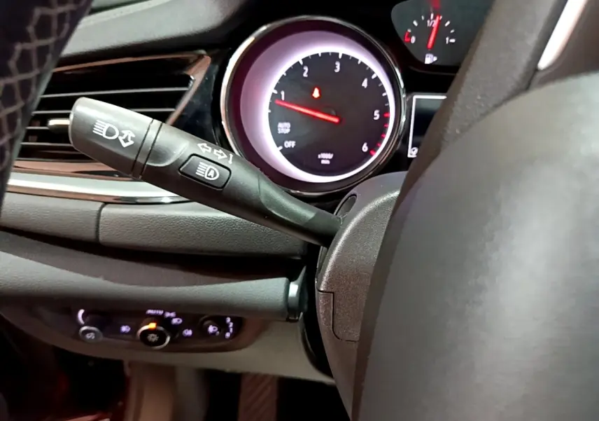 Gros plan sur la commande des phares et clignotants à gauche du volant de l’Opel Insignia, tableau de bord en arrière-plan.