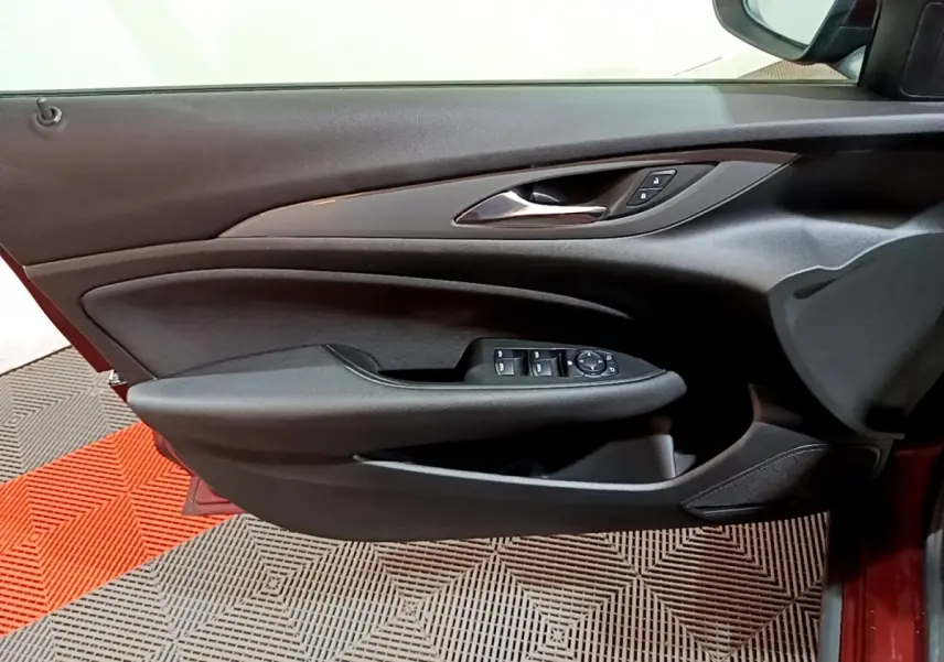 Vue intérieure du panneau de porte conducteur noir d’une Opel Insignia rouge, avec commandes des vitres et rétroviseurs.