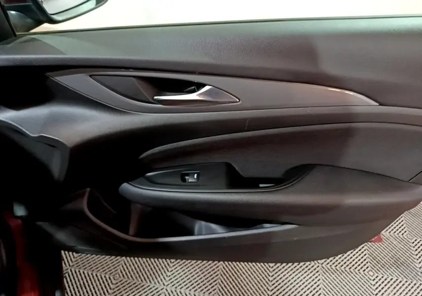 Vue rapprochée de la porte côté conducteur de l’Opel Insignia rouge, avec poignée argentée et commande de vitre.