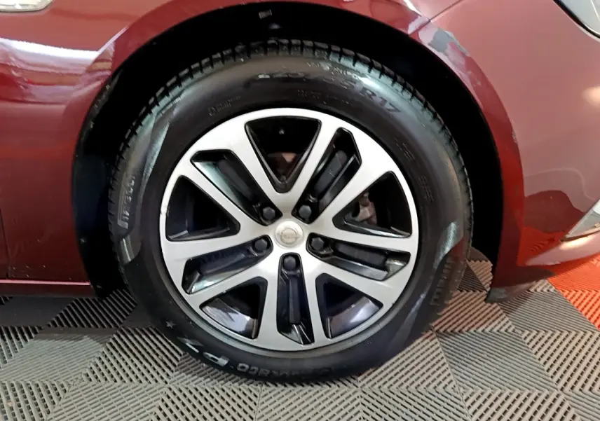 Gros plan sur la roue avant gauche d’une Opel Insignia rouge, mettant en valeur la jante alliage bicolore.