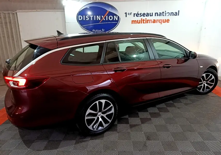 Opel Insignia rouge vue de profil droit en break, avec jantes alliage et feux arrière allumés.