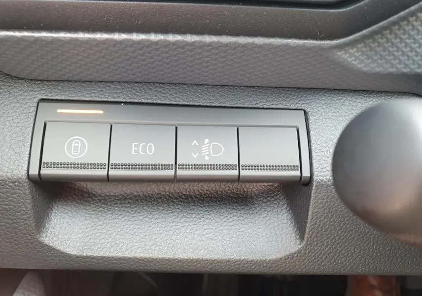 Boutons de commande du tableau de bord du Dacia Dokker Van 2026, avec mode ECO et réglage des phares visibles.