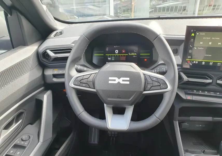 Vue intérieure centrée sur le volant et le tableau de bord numérique du Dacia Dokker Van gris schiste, avec écran tactile visible.