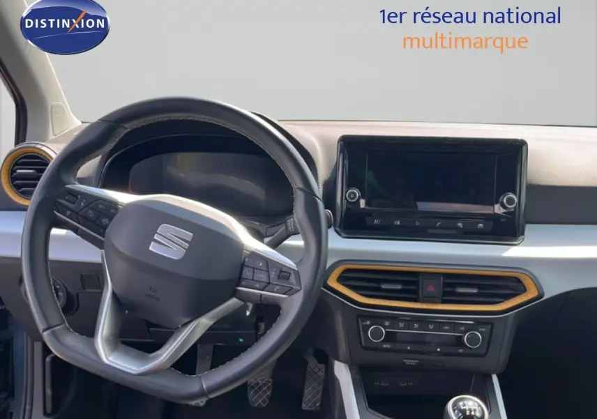 Vue intérieure du poste de conduite du SEAT Arona 2025, volant multifonction noir et tableau de bord avec écran tactile.