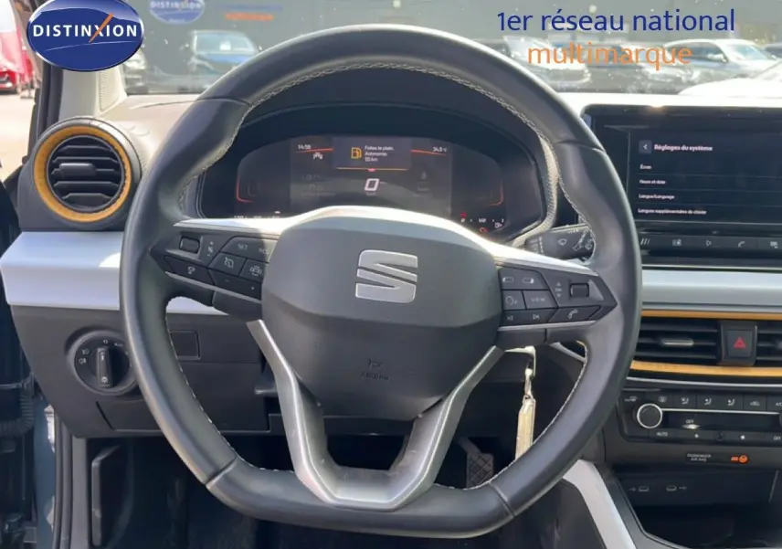 Vue centrée sur le volant noir de la SEAT Arona 2025, avec tableau de bord digital et détails intérieurs jaunes.