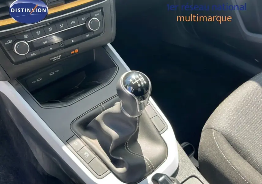 Gros plan sur la console centrale du SEAT Arona 2025 avec levier de vitesse manuel et sellerie tissu gris.