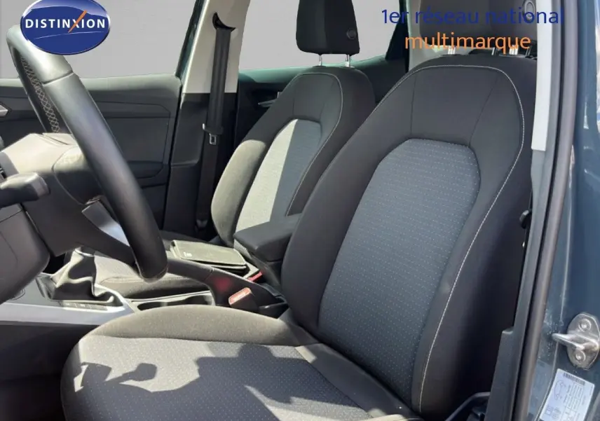 Vue intérieure côté conducteur du SEAT Arona 2025 bleu Fjord, montrant les sièges tissu gris noir et la boîte manuelle.
