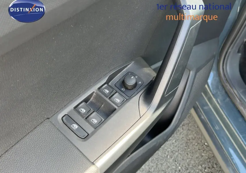 Gros plan sur les commandes de lève-vitres et réglage des rétroviseurs côté conducteur d’un SEAT Arona bleu Fjord.
