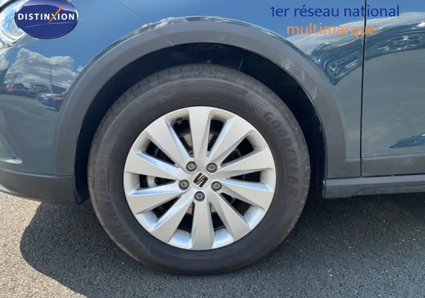 Gros plan sur la roue avant gauche d’un SEAT Arona bleu Fjord avec jante argentée et logo central Seat.