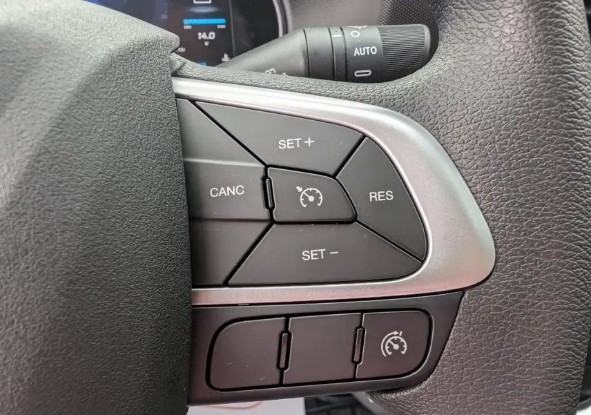 Gros plan sur les commandes du régulateur de vitesse au volant du Iveco Daily blanc, intérieur moderne avec écran digital partiel visible.