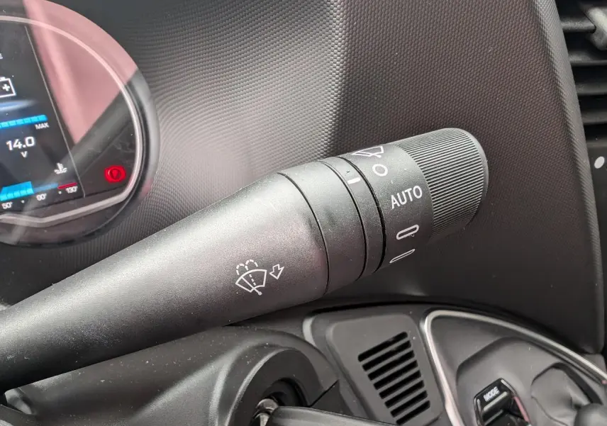 Gros plan sur la manette d’essuie-glace noire à droite du volant dans l’habitacle du Iveco Daily blanc.