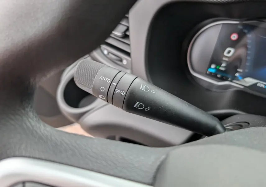 Gros plan sur la commande d’éclairage automatique noire à gauche du volant dans l’habitacle du Iveco Daily blanc.